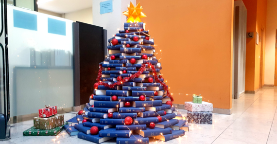 Baum aus blauen Büchern mit Lichterkette in der Bibliothek